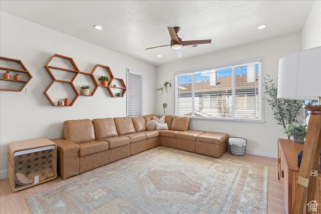 Living room featuring light hardwood / wood-style floors, ceiling fan, and a textured ceiling