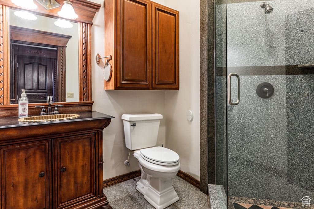 Bathroom with toilet, a shower with door, and vanity with extensive cabinet space