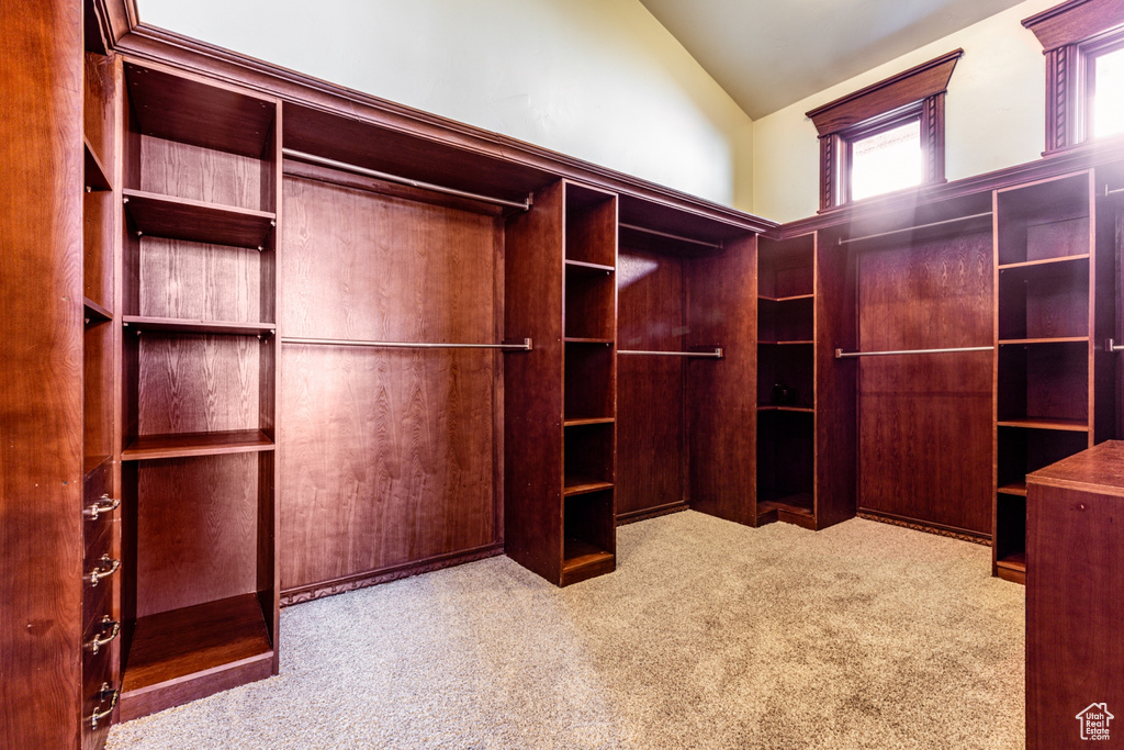 Walk in closet with light carpet and lofted ceiling
