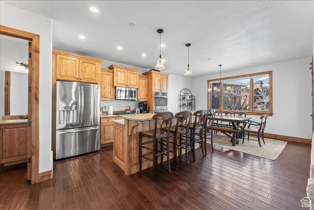 Kitchen with dark hardwood / wood-style floors, appliances with stainless steel finishes, and light stone counters