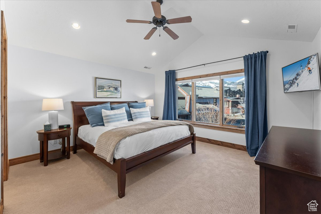Bedroom with light carpet, ceiling fan, and vaulted ceiling