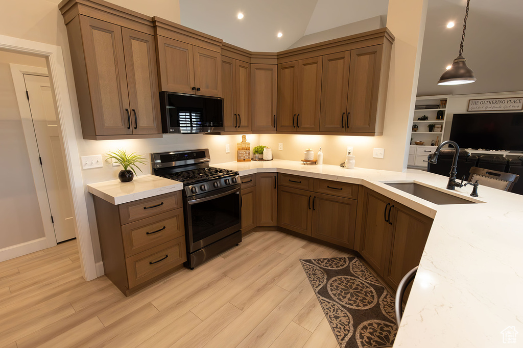 Kitchen with gas range oven, light hardwood / wood-style flooring, sink, and pendant lighting