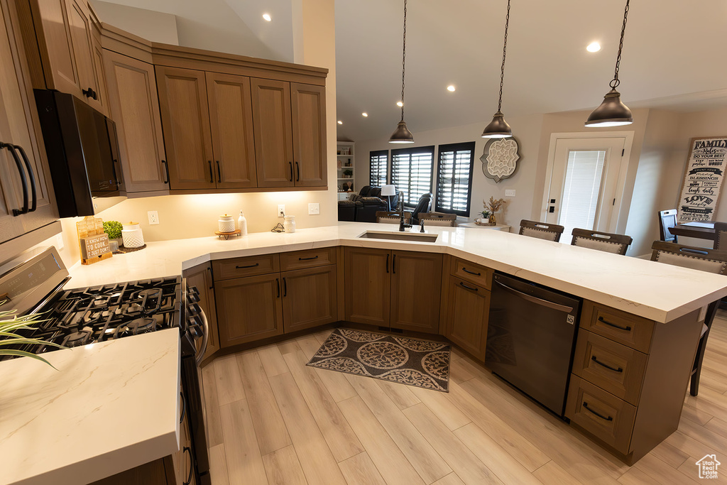 Kitchen with pendant lighting, range, a breakfast bar, light wood-type flooring, and sink