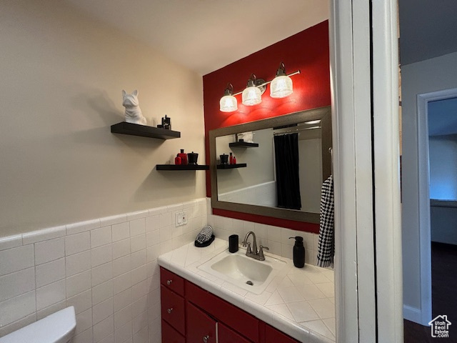 Bathroom featuring vanity, backsplash, toilet, and tile walls
