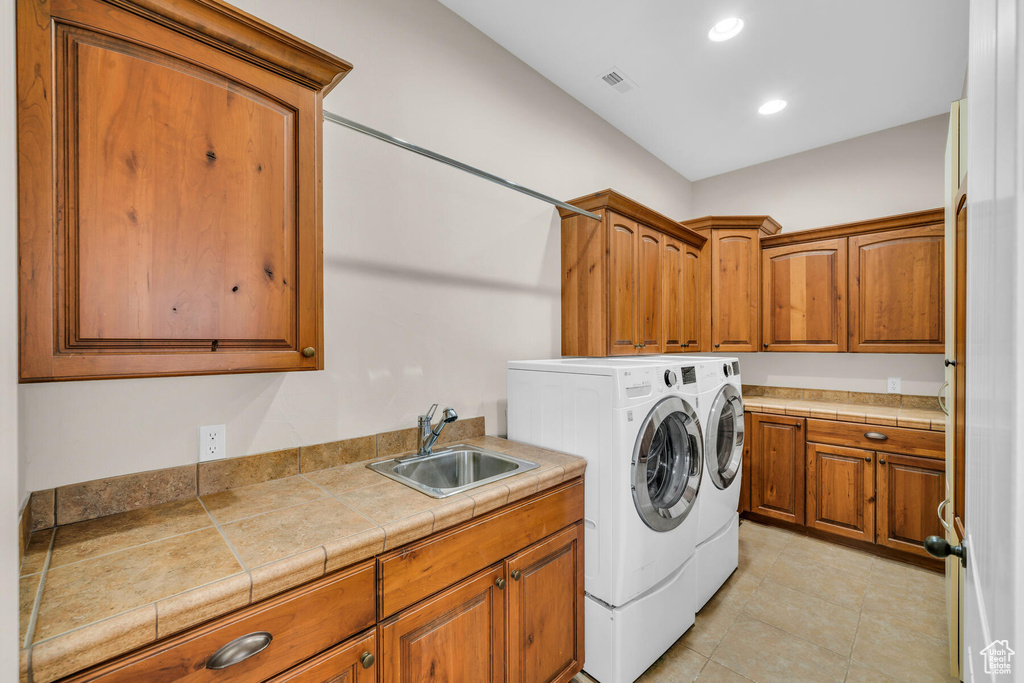 Laundry area featuring light tile flooring, independent washer and dryer, cabinets, and sink