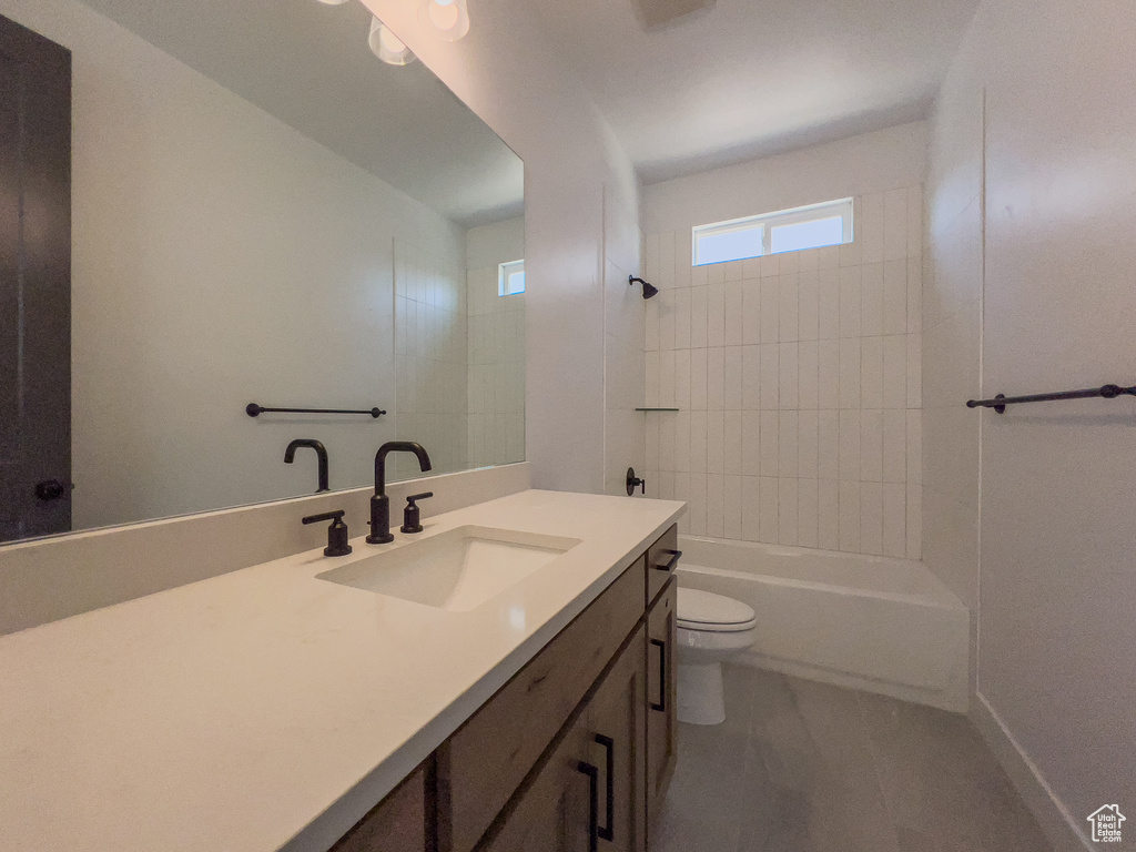 Full bathroom featuring tiled shower / bath, toilet, tile floors, and oversized vanity