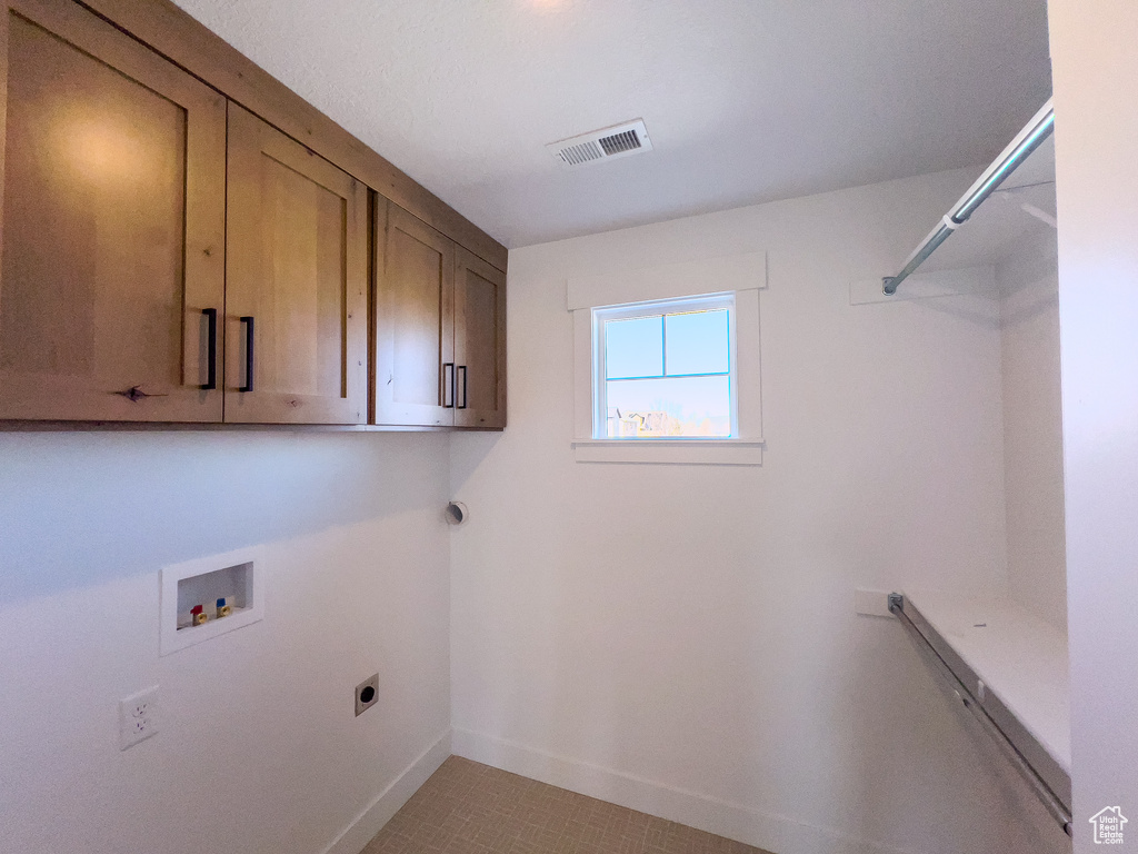 Laundry room with washer hookup, electric dryer hookup, light tile flooring, and cabinets