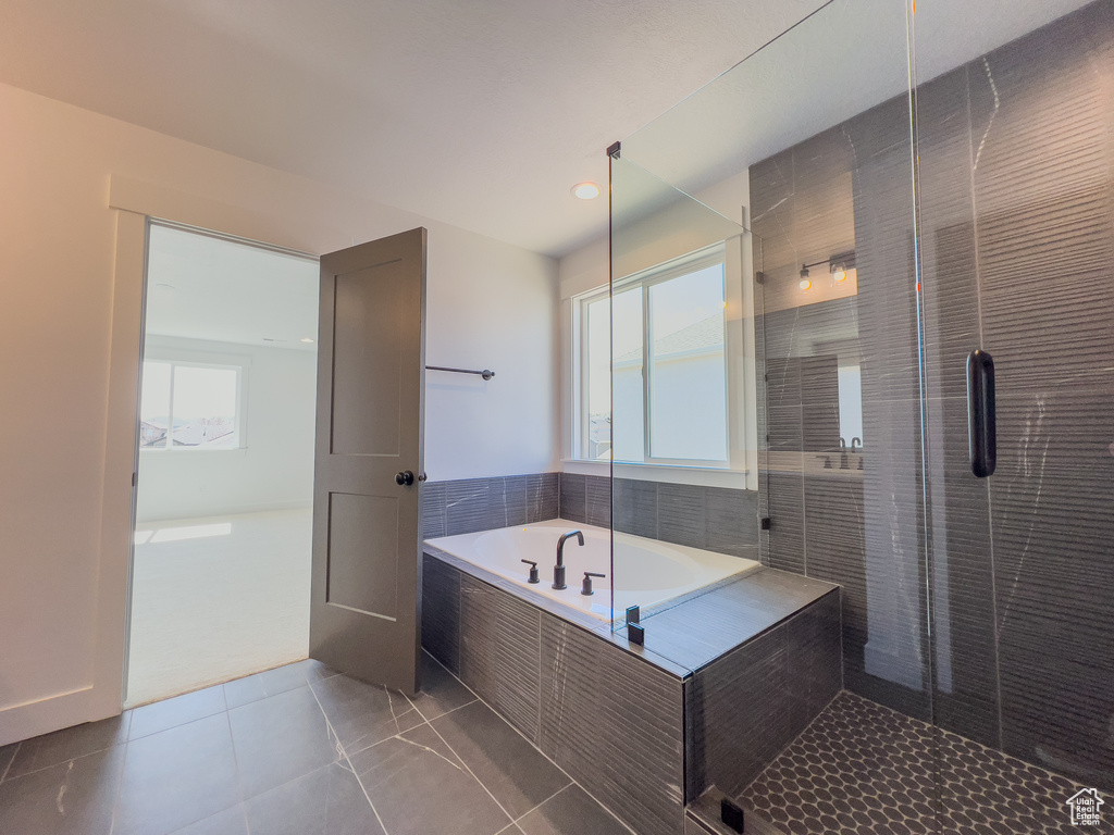 Bathroom featuring shower with separate bathtub, tile floors, and a wealth of natural light