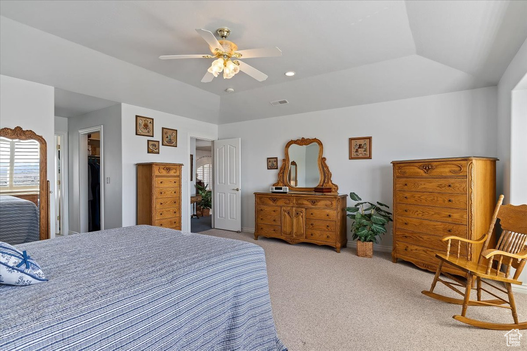 Carpeted bedroom with a closet, a walk in closet, ceiling fan, and vaulted ceiling