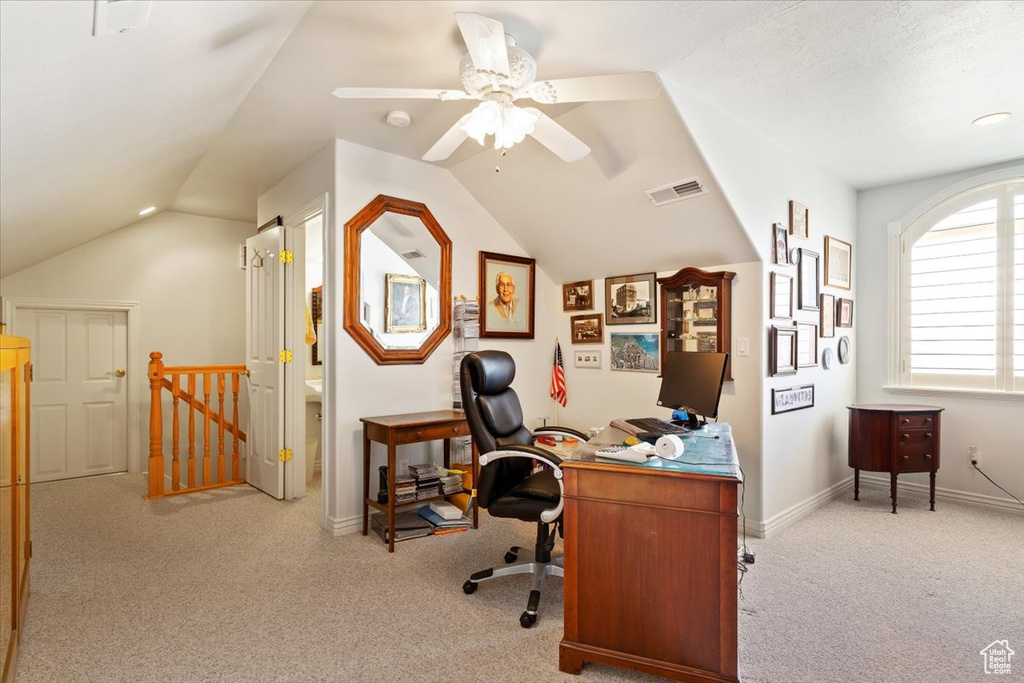 Office space featuring light carpet, ceiling fan, and vaulted ceiling