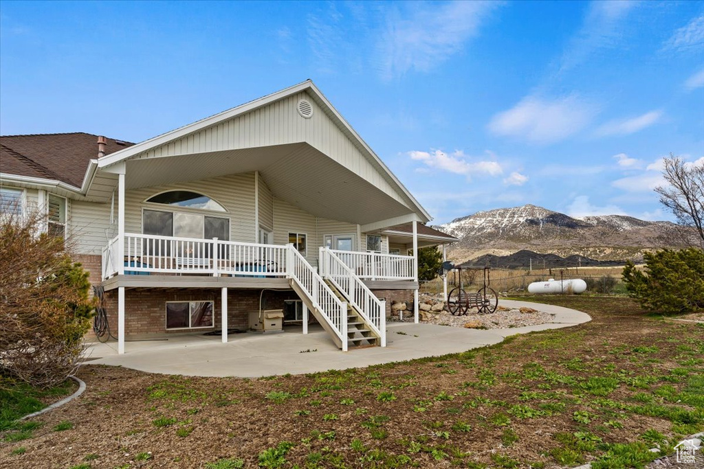 Back of property featuring a deck with mountain view and a patio area