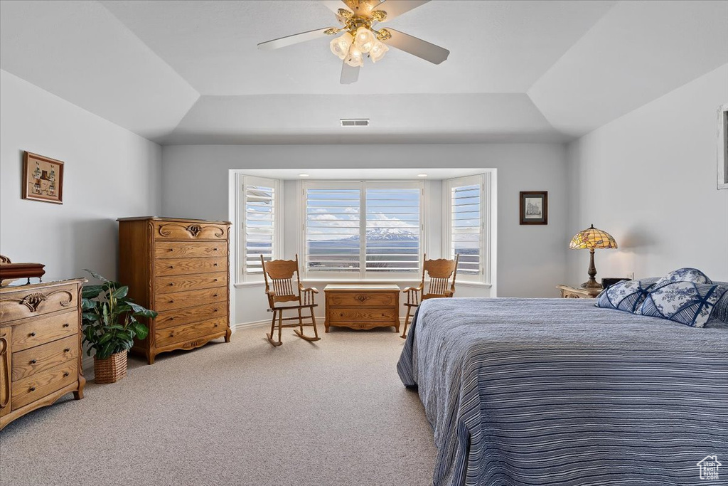 Bedroom with light carpet, ceiling fan, a tray ceiling, and lofted ceiling