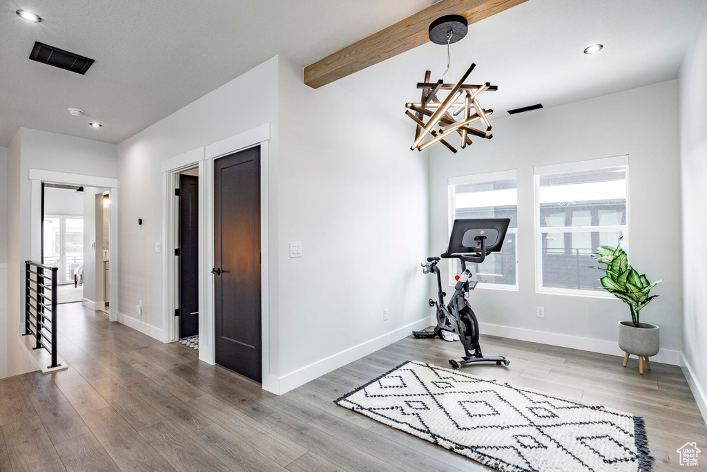 Workout room with a chandelier and light wood-type flooring