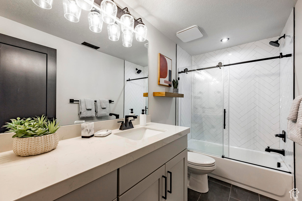 Full bathroom with toilet, tile flooring, shower / bath combination with glass door, a textured ceiling, and vanity