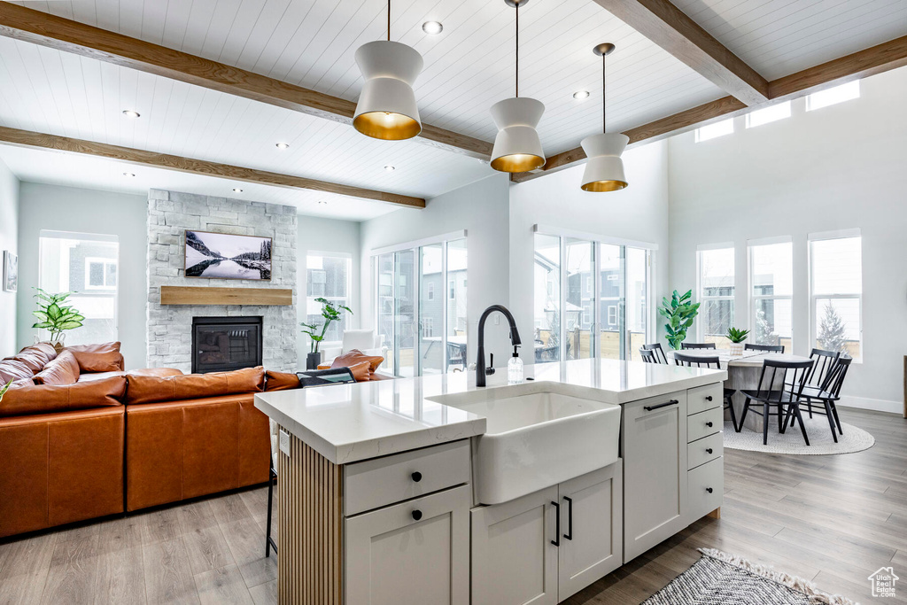 Kitchen featuring light hardwood / wood-style flooring, decorative light fixtures, an island with sink, and a fireplace