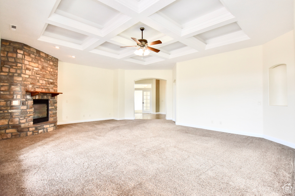 Unfurnished living room featuring coffered ceiling, a large fireplace, carpet flooring, and beamed ceiling