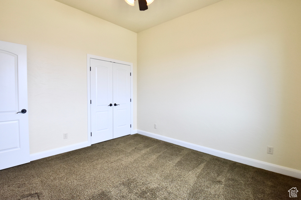 Unfurnished bedroom featuring a closet, ceiling fan, and dark carpet