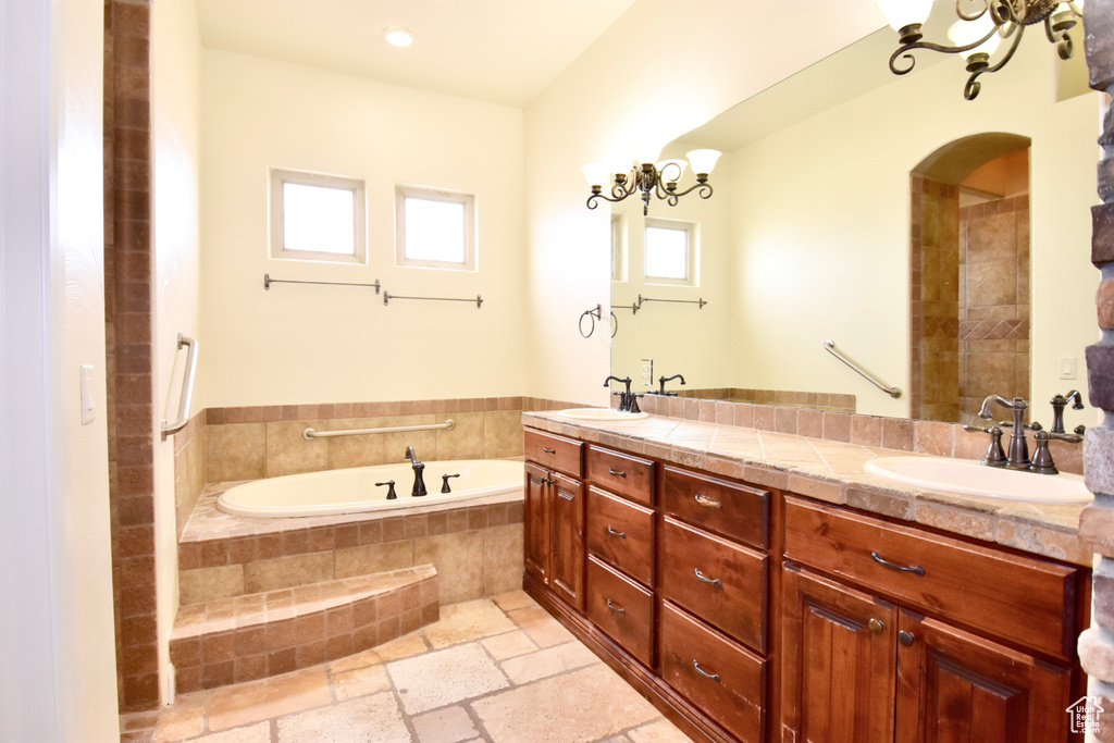 Bathroom with double sink vanity, tile floors, and tiled bath