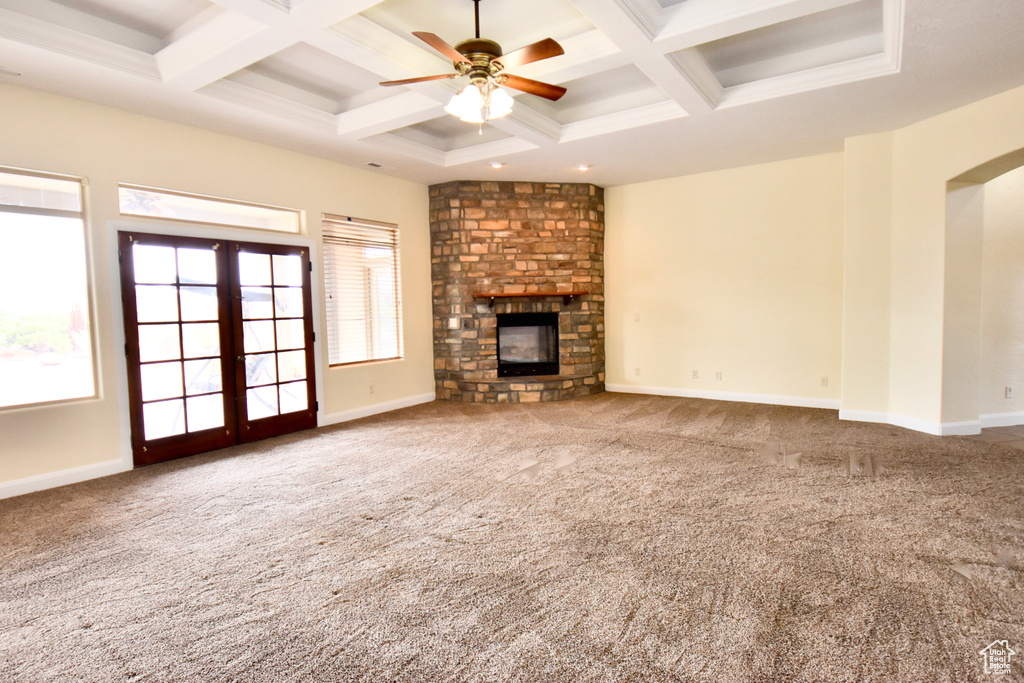 Unfurnished living room featuring coffered ceiling, dark carpet, ceiling fan, and a fireplace