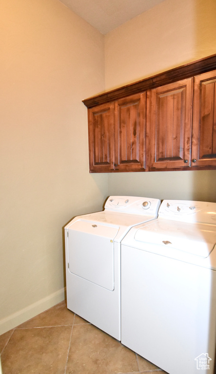 Washroom featuring light tile flooring, cabinets, and independent washer and dryer