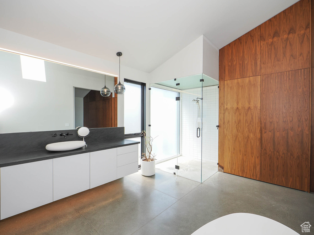 Bathroom featuring concrete floors, vanity, a shower with shower door, and lofted ceiling