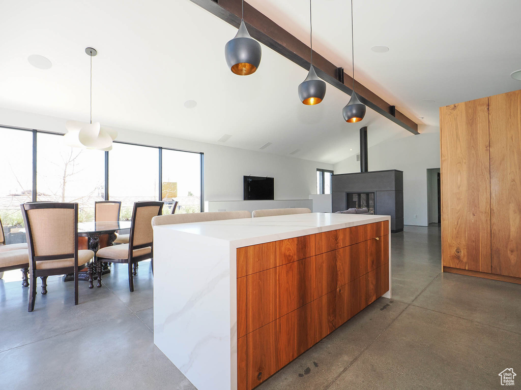 Kitchen with decorative light fixtures, concrete floors, and vaulted ceiling with beams
