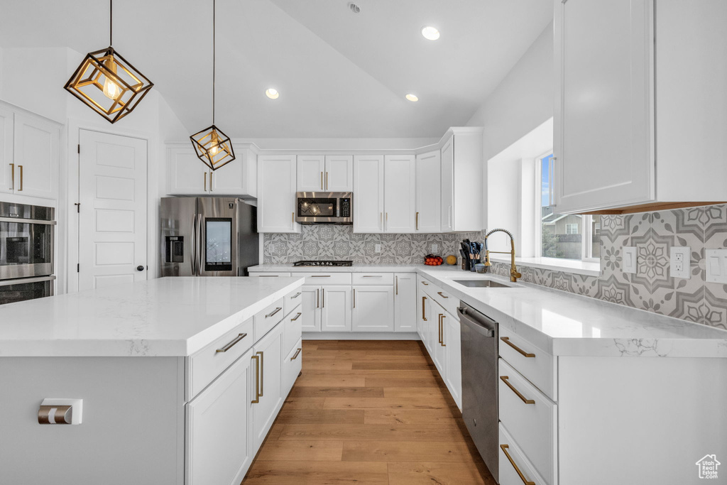Kitchen featuring tasteful backsplash, appliances with stainless steel finishes, light hardwood / wood-style floors, and sink