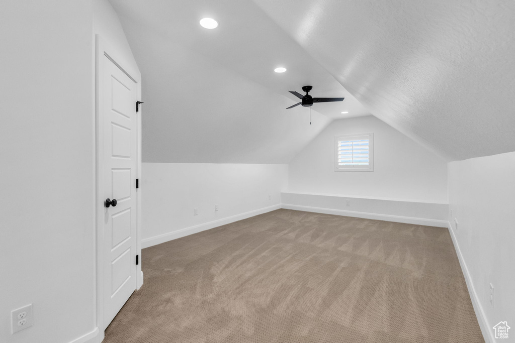 Additional living space with vaulted ceiling, a textured ceiling, ceiling fan, and carpet floors