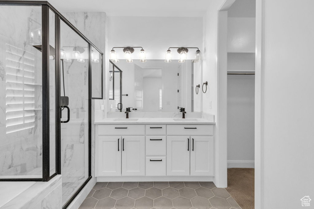 Bathroom with double sink vanity, an enclosed shower, and tile flooring