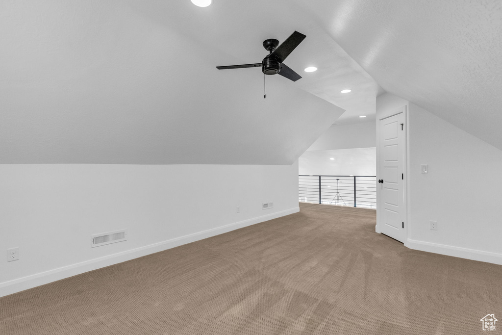 Bonus room with vaulted ceiling, ceiling fan, and carpet
