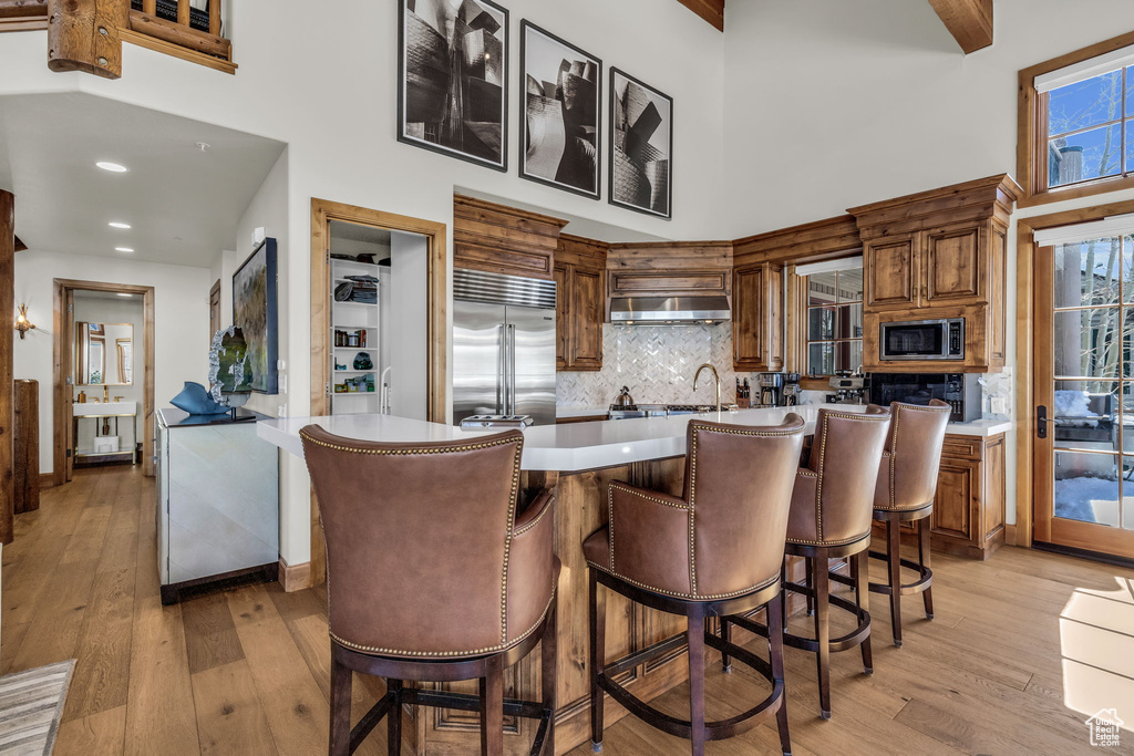Kitchen with built in appliances, light hardwood / wood-style floors, and a breakfast bar