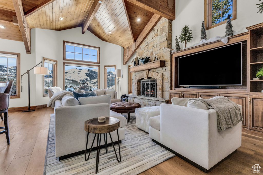 Living room featuring a mountain view, wood ceiling, a fireplace, high vaulted ceiling, and light wood-type flooring
