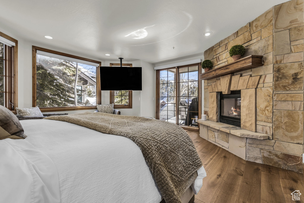 Bedroom featuring dark hardwood / wood-style flooring, a stone fireplace, and access to outside