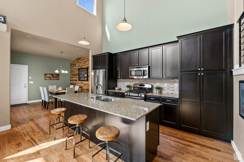 Kitchen featuring a kitchen breakfast bar, a chandelier, light wood-type flooring, and stainless steel appliances