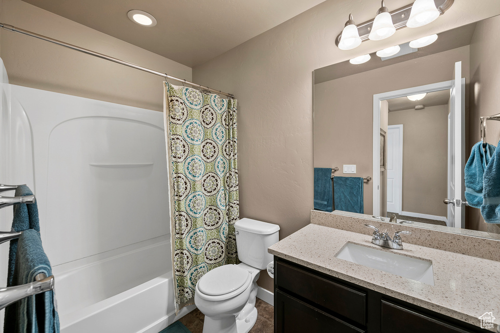Full bathroom with tile flooring, large vanity, toilet, and shower / bathtub combination with curtain