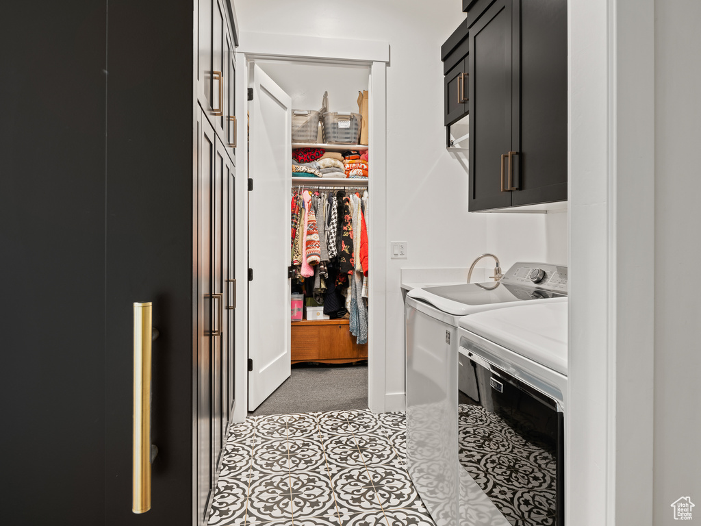 Laundry room featuring independent washer and dryer, light tile floors, and cabinets