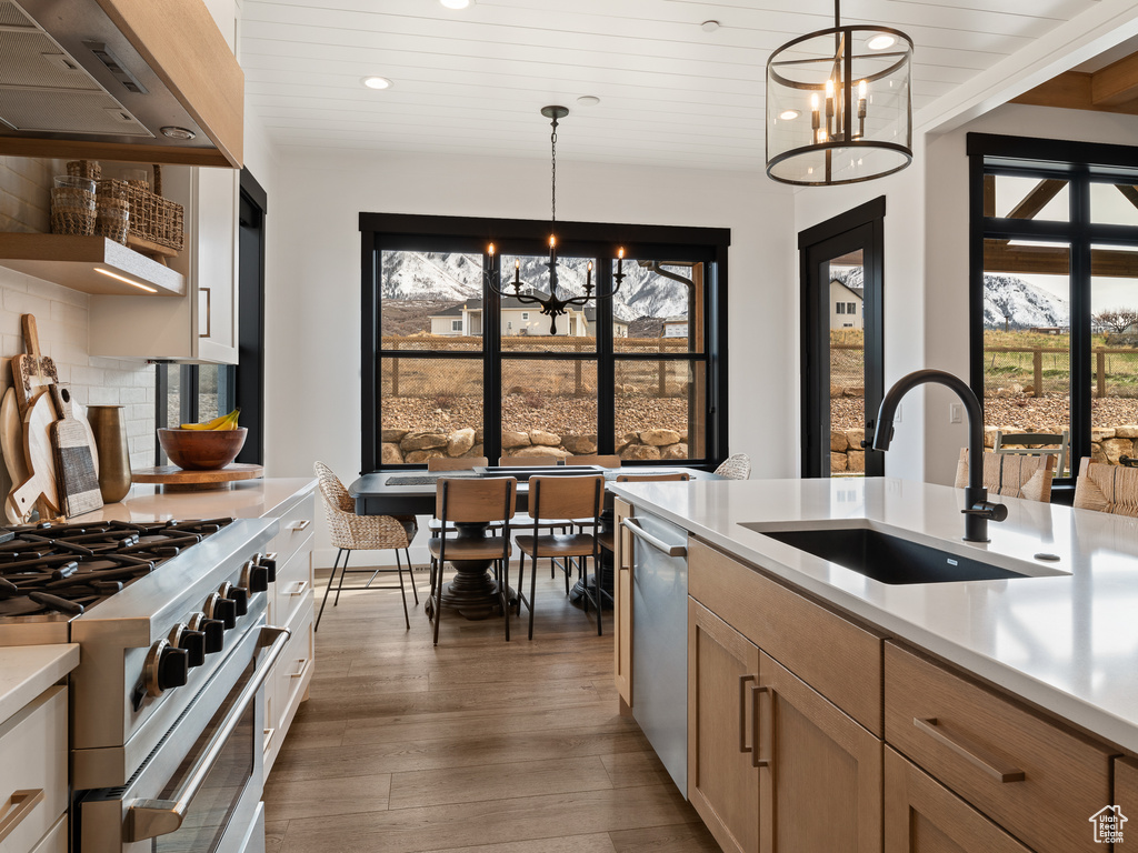 Kitchen with decorative light fixtures, wood-type flooring, sink, a chandelier, and tasteful backsplash