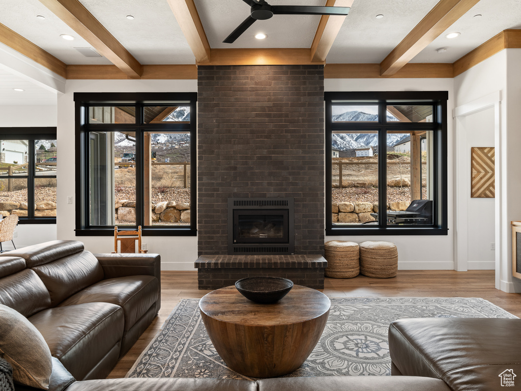 Living room featuring hardwood / wood-style floors, a healthy amount of sunlight, ceiling fan, and a fireplace