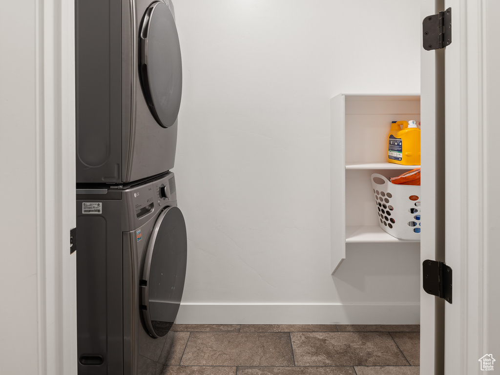 Washroom featuring dark tile flooring and stacked washer / drying machine