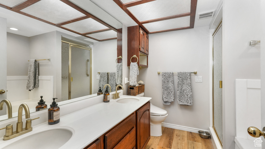 Bathroom with an enclosed shower, double sink vanity, wood-type flooring, and toilet