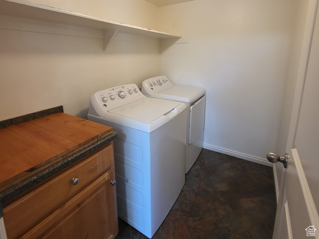 Laundry room with cabinets, dark tile floors, and washer and dryer