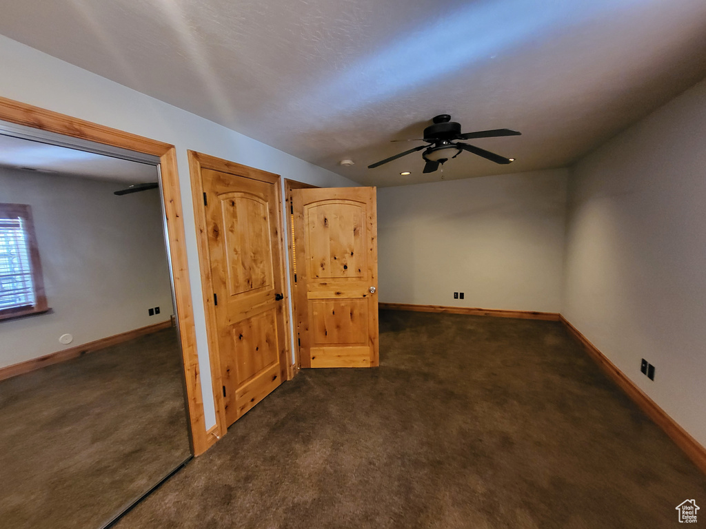 Basement featuring dark carpet and ceiling fan