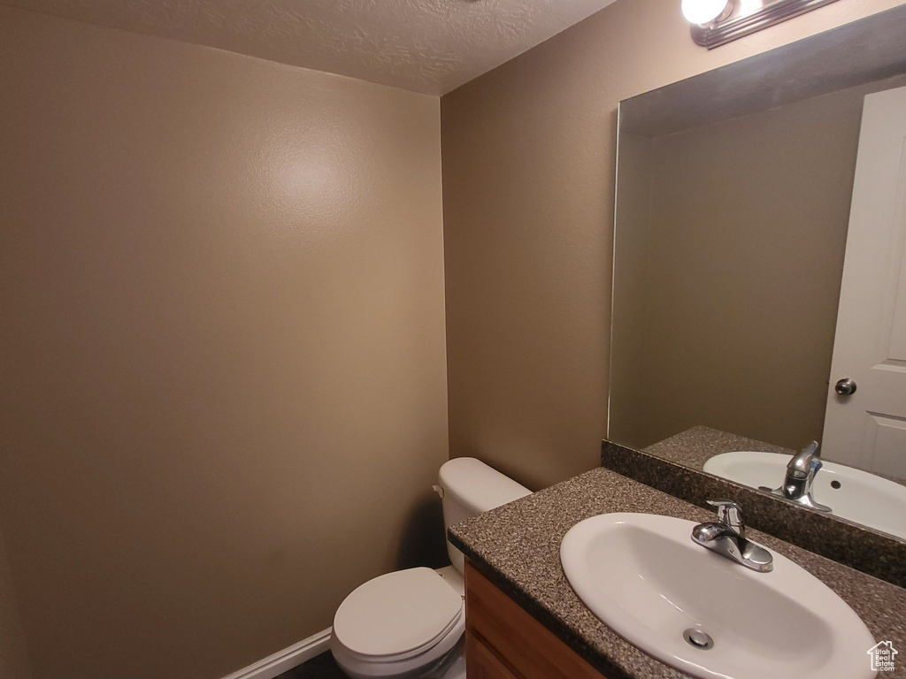 Bathroom featuring toilet, large vanity, tile floors, and a textured ceiling