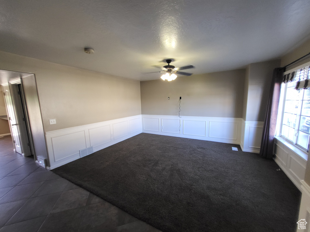 Unfurnished room featuring dark tile floors and ceiling fan