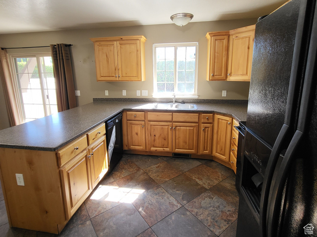 Kitchen featuring a textured ceiling, kitchen peninsula, black appliances, dark tile flooring, and sink