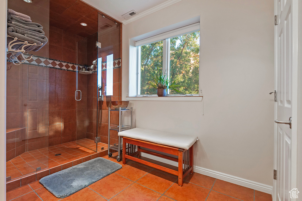 Bathroom featuring tile flooring, ornamental molding, and a shower with shower door