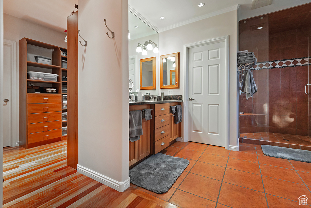 Bathroom with tile floors, crown molding, vanity with extensive cabinet space, and tiled shower
