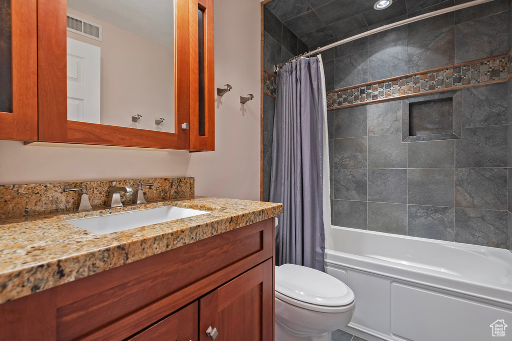 Full bathroom featuring toilet, shower / tub combo with curtain, and vanity