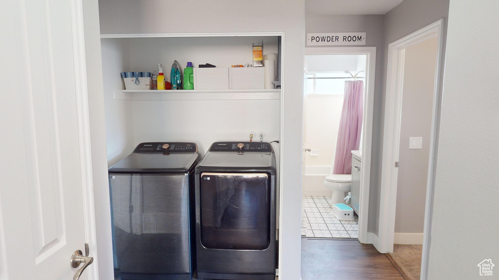 Clothes washing area with hardwood / wood-style floors and independent washer and dryer