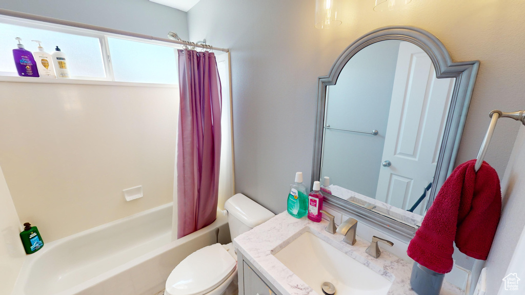 Full bathroom with toilet, shower / bathtub combination with curtain, and vanity with extensive cabinet space